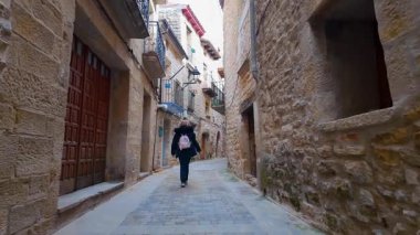 Arkadan gelen kadın turist, ortaçağ Kretas kasabası Teruel Matarrana 'nın sokaklarında geziniyor.