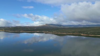 Güzel durgun su gölü ve fırtına bulutları ile mavi gökyüzünün yansımaları, El Atazar, Madrid