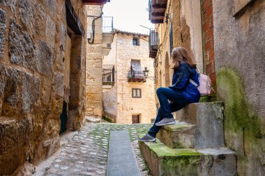 Ortaçağ Valderrobres köyünün kaldırımlı bir sokağında oturan ve dinlenen turist kadın Teruel