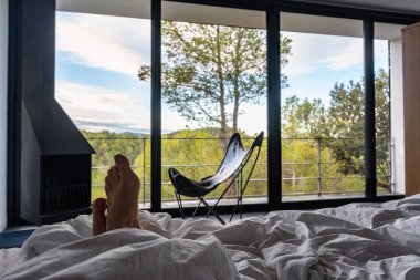 Gündoğumunda ormanın muhteşem manzarasıyla yatakta dinlenen bir insan..