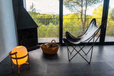 Güneş doğarken ormana bakan odunlu ve şezlonglu şömine..