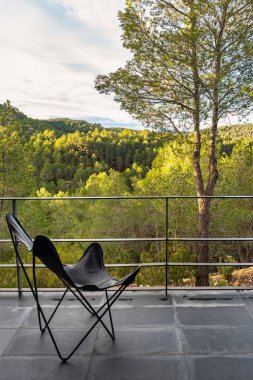 Şafakta ormanın muhteşem manzarasının tadını çıkarmak için sandalyeli teras.