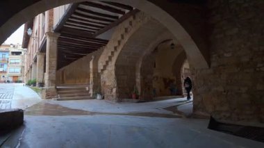 Turist kadın, Rafales, Teruel 'in ortaçağ köyünde taş kemerlerle atari salonlarında geziniyor.