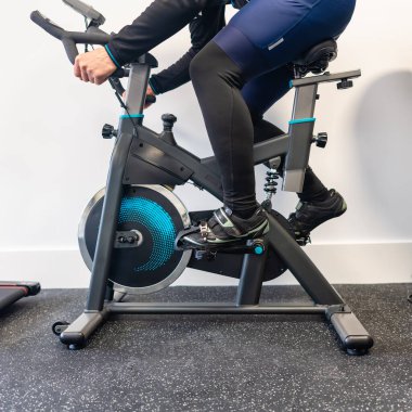 Olgun bir adam evde egzersiz bisikleti üzerinde bacak egzersizi yapıyor.