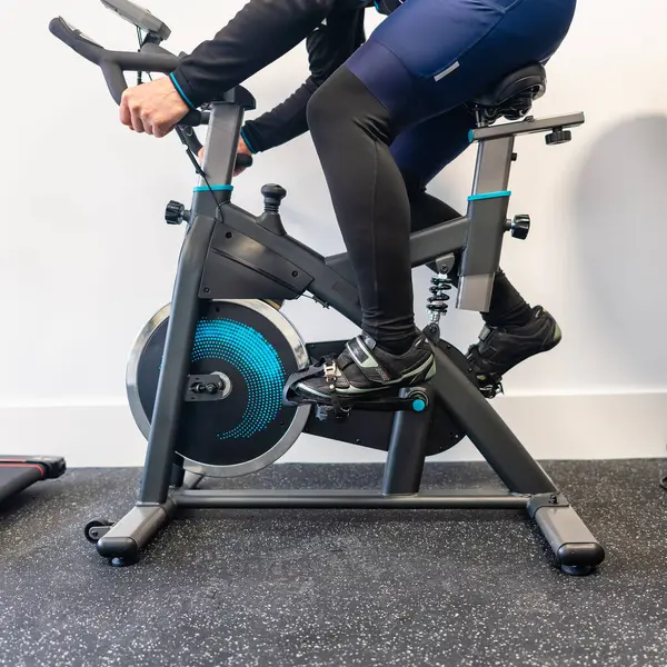 Olgun bir adam evde egzersiz bisikleti üzerinde bacak egzersizi yapıyor.