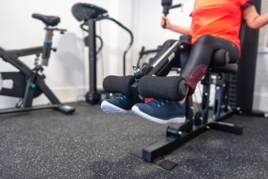 Kadının bacakları evdeki ağırlık makinesinde vücut geliştirme yapıyor.