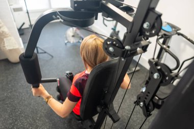 Sırtüstü uzanmış, evinde ağırlık makinesiyle egzersiz yapan bir kadın.