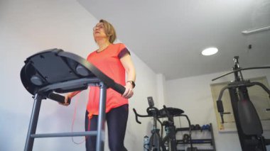 Formda kalmak için evinde koşu bandında yürüyen kıdemli bir kadın.