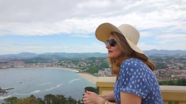 San Sebastian, Bask Bölgesi 'nde La Concha Körfezi' ne bakan balkondan sarkan turist kadın.