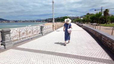 Ondarreta plajı boyunca geriye doğru yürüyen kadın, San Sebastian, Bask Ülkesi