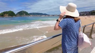 Şapkalı turist kadın La Concha Körfezi manzarasını seyrediyor, San Sebastian, İspanya