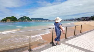 Elbiseli bir kadın La Concha, San Sebastian, Bask Ülkesi 'nde yavaşça yürüyor.