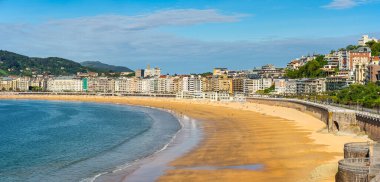 Güneşli bir yaz gününde, San Sebastian 'da kumsalda gezinen insanlarla dolu kocaman bir La Concha plajı.