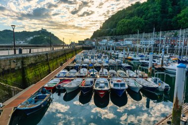 San Sebastian limanında gün batımında sakin sulara park edilmiş küçük tekneler.
