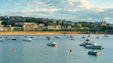 San Sebastian, Bask Bölgesi 'nde sakin sularda demirli teknelerle La Concha Körfezi üzerinde güzel bir günbatımı..