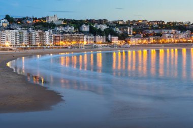 San Sebastian şehri, deniz suyuna yansıyan binaların ışıklarıyla, Bask Ülkesi.