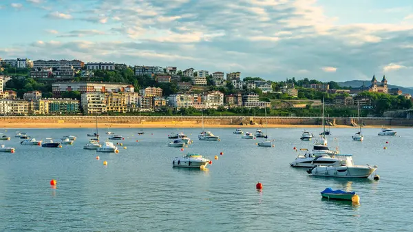 San Sebastian, Bask Bölgesi 'nde sakin sularda demirli teknelerle La Concha Körfezi üzerinde güzel bir günbatımı..