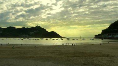 La Concha sahilinde günbatımının panoramik görüntüsü. Arka planda Igueldo Dağı, San Sebastian.