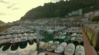 San Sebastian limanında gün batımında sakin sulara park edilmiş küçük tekneler.