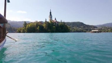 Güneşli bir günde, Slovenya 'nın mavi gökyüzüyle gölde kürek çeken bir tekne gezisi.