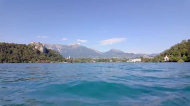 Slovenya 'nın güneşli bir yaz gününde, göl boyunca ilerleyen kayıkları görmek...