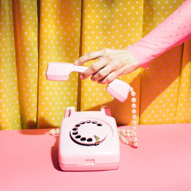 Kaliteli döner telefon ve kadın eli, şeker pembesi arka planına karşı retro stil estetik düzen. Romantik nostalji.