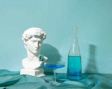 Zarif Art Deco kokteyl bardağı ve mavi içecekle şişe, erkek dekoratif büst, antika güzellik esinlenilmiş, yaratıcı yaz egzotik serinleme düzeni.