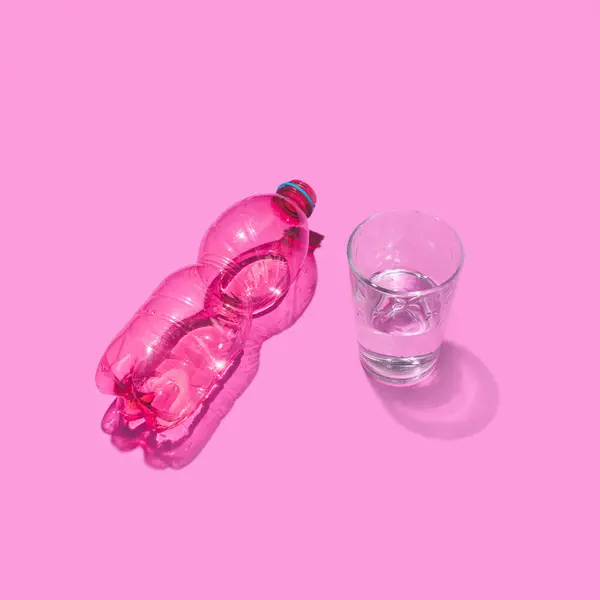 塑料瓶和杯子水 创意布局与糖果粉红背景 — 图库照片