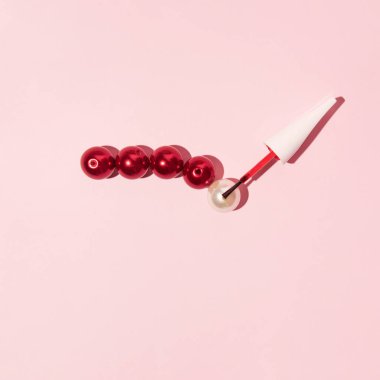 İnci boncuklar ve oje fırçası, yaratıcı estetik güzellik konsepti. Tırnak boyamak mükemmel bir fikir. Şeker pembe arkaplan.