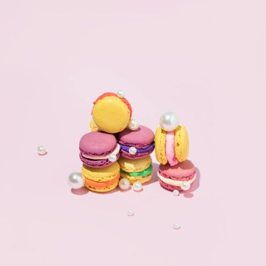 Renkli badem kurabiyeleri, geleneksel Fransız kurabiyeleri. İnci ve mücevherlerle yaratıcılıkla düzenlenmiş. Pastel pembe arka plana karşı romantik estetik düzen..