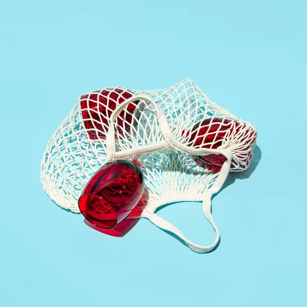 Mesh bag, red elegant wine glasses in it, creative aesthetic layout, party time.