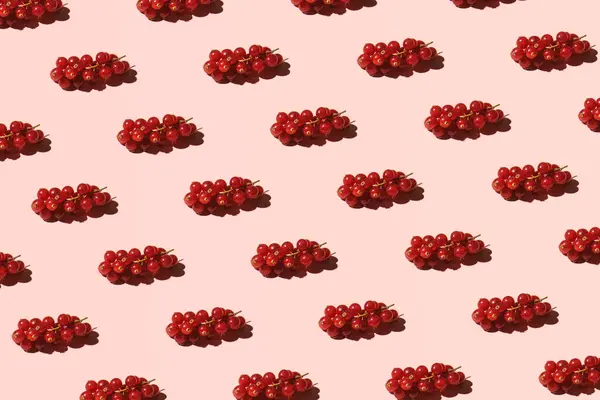 Red currant, fresh red berries, creative fruit pattern, pastel pink background.