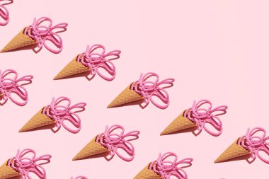 Dondurma külahları, pembe örgülü ip yaratıcı bir şekilde yerleştirilmiş, eriyen meyveli dondurma fikri, deniz piyadesi esinlenilmiş, yaz tatili deseni, şeker pembesi arka plan.