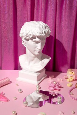 Genç adamın heykeli, antik güzellik, pembe arka planda dekoratif unsur, parlak disko pembe kumaş örtüsü..