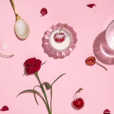 Meyve ve çiçeklerin yaratıcı düzeni. Kirazlı yoğurt, pastel pembe arka plan.