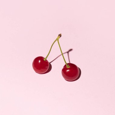 Kirazlar, en az yaratıcı bahar meyvesi düzeni, pastel pembe arka plan..