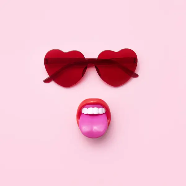 ハートの形をした赤いサングラス 舌が突き出し 創造的な夏のファッションのトレンドのレイアウト パステルピンクの背景 — ストック写真