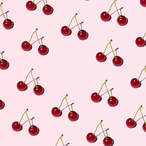 Fresh cherries, summer fruit pattern with creative copy space, cute romantic layout, pastel pink background.