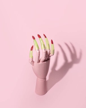 Yaratıcı, estetik cadılar bayramı kutlama planı. Bir cadının keskin tırnaklı kadın eli modeli, duvarında korkunç bir siluet, pastel pembe arka plan.. 