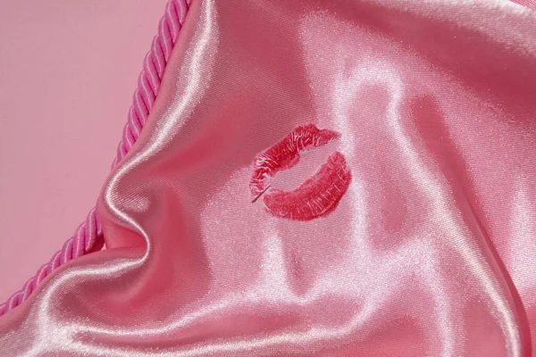 A lipstick print, creative aesthetic love and passion concept, girl\'s kiss on pastel pink satin sheet.