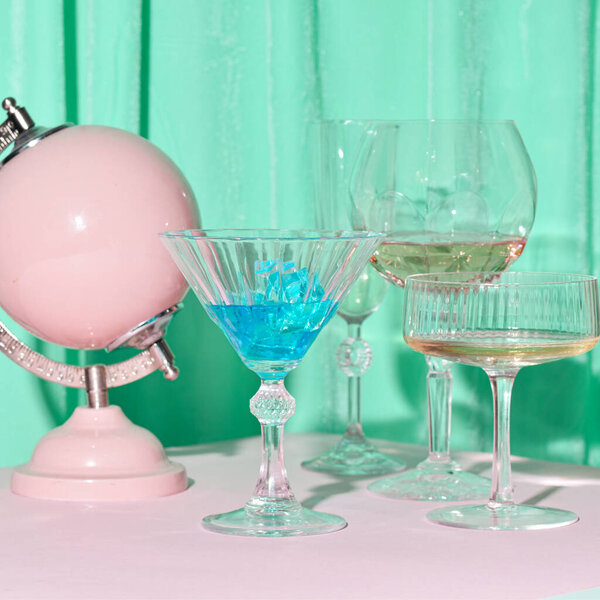 Set of glasses for martini cocktail on a blue background, pink globe decoration.