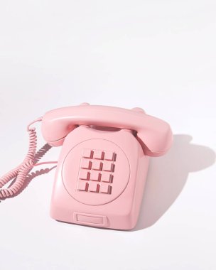 Beyaz arkaplanda eski pembe telefon. 