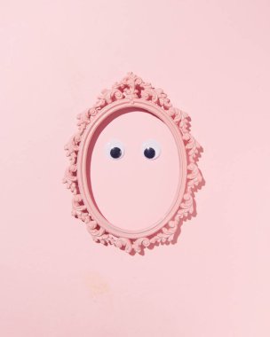 Bir çift göz oval vintage resim çerçevesi içinde, minimalist portre konsepti, pastel pembe arka plan.