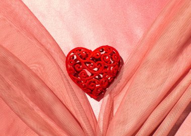 Yaka şeklinde örülmüş hassas ağ kumaşı ortada kırmızı dekoratif kalp yaratıcı romantik düzen, şeftali tüyü arka plan..