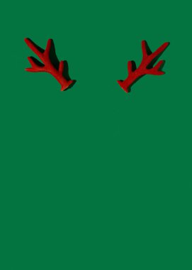 Yeşil arka planda kırmızı ren geyiği boynuzları, minimalist kış tatili kompozisyonu, Noel konsepti.