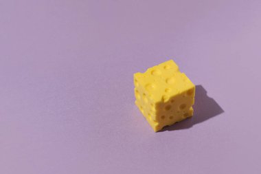 Mor arka planda delikleri olan bir küp peynir..