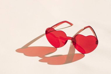 Beyaz arkaplanda güneş gözlüğü ve kırmızı kalp şeklinde çerçeve