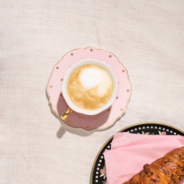 Bir fincan kapuçino ve taze pişmiş kruvasan.