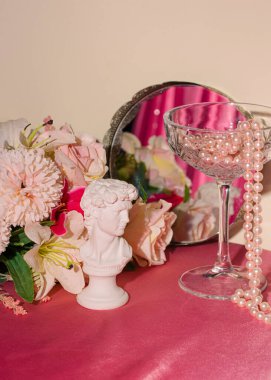 Rönesans sanatının bir parçası, klasik çerçeve aynası, kristal şampanya kadehi, çiçekler, pastel pembe arka planda inciler. Retro lüks estetik