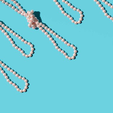 Parlak mavi arkaplanda zarif inci kolyeler.